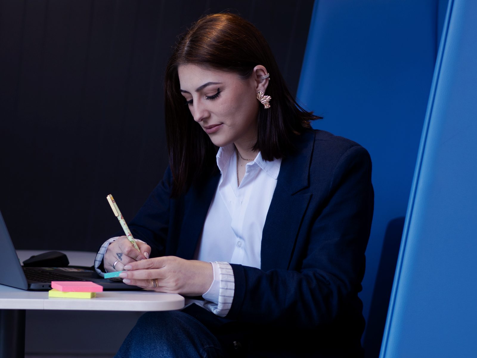 Dheniffer Vieira escrevendo anotações em post-its ao lado do notebook durante sessão de estratégia